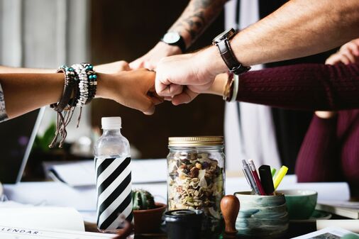 5 peoples fists in center across work table